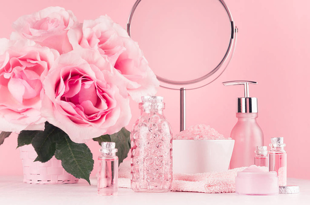 Cosmetic products for aromatherapy, spa salon - essential rose oil, bath salt, cream, soap, bath accessories with round mirror, roses in pink color on white wood board. - Fotografie, Obrázek
