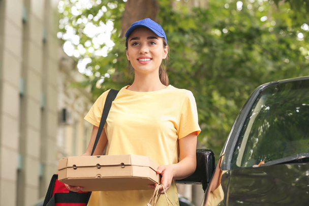 Female worker of food delivery service near car outdoors - Zdjęcie, obraz