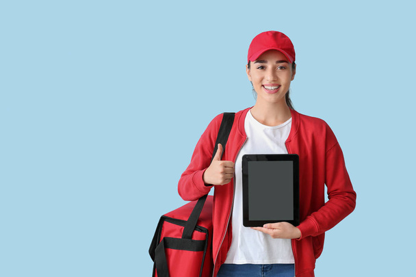 Vrouwelijke werknemer van Food delivery service met Tablet computer op kleur achtergrond - Foto, afbeelding