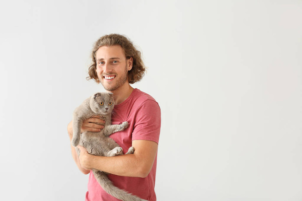 Man with cute funny cat on light background - Photo, Image
