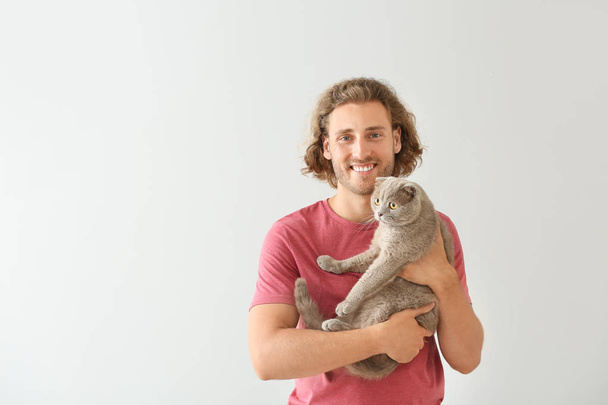 Man with cute funny cat on light background - Photo, Image