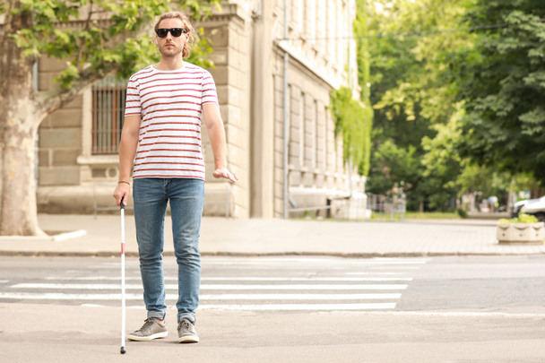 Сліпий молодий чоловік виходить на вулицю
 - Фото, зображення