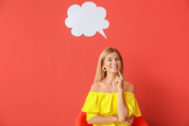 Happy woman sitting in armchair near speech bubble on color background - Foto, immagini