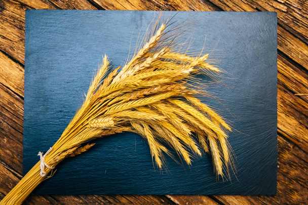 Ear of wheat or spike on the black background wooden table. Bakery or bread concept image. - Photo, image