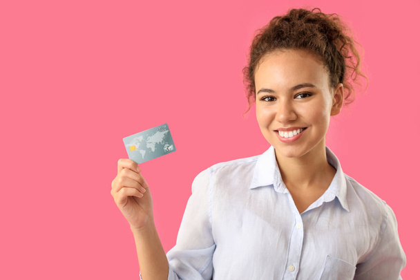 glücklich afrikanisch-amerikanische Frau mit Kreditkarte auf farbigem Hintergrund - Foto, Bild