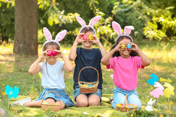 Pienet lapset keräävät pääsiäismunia puistossa
 - Valokuva, kuva