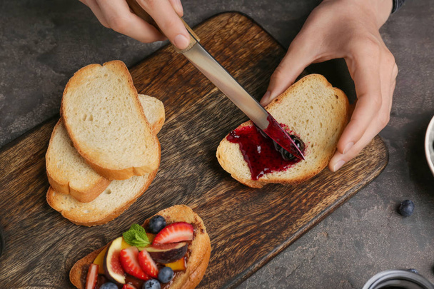 Woman spreading tasty berry jam onto toasted bread, closeup - Fotoğraf, Görsel