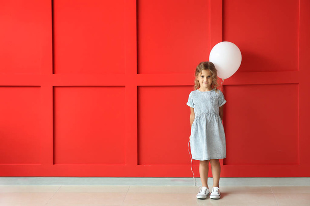 Κοριτσάκι με μπαλόνι κοντά στον τοίχο χρώμα - Φωτογραφία, εικόνα