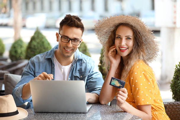 Jeune couple avec carte de crédit et ordinateur portable assis dans un café
 - Photo, image