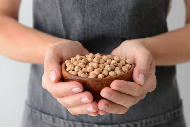 Woman holding bowl with raw chickpea, closeup - Photo, image