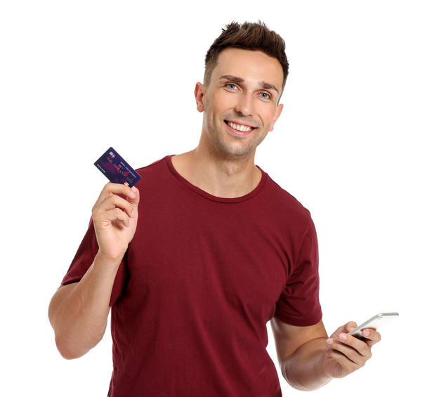 Młody człowiek z kartą kredytową i telefonem komórkowym na białym tle - Zdjęcie, obraz