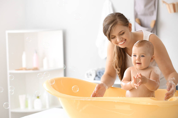 Mutter badet ihr süßes kleines Baby zu Hause - Foto, Bild