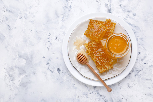 Piatto con miele dolce e pettini sul tavolo
 - Foto, immagini