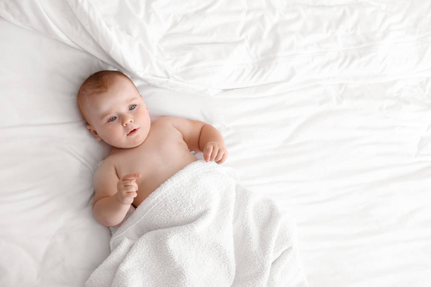 Χαριτωμένο μωρό μετά το μπάνιο ξαπλωμένο στο κρεβάτι - Φωτογραφία, εικόνα