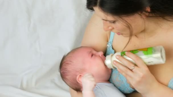 Двомісячна новонароджена дитина лежить на руках матері і смокче сосок з пляшки молока
 - Кадри, відео