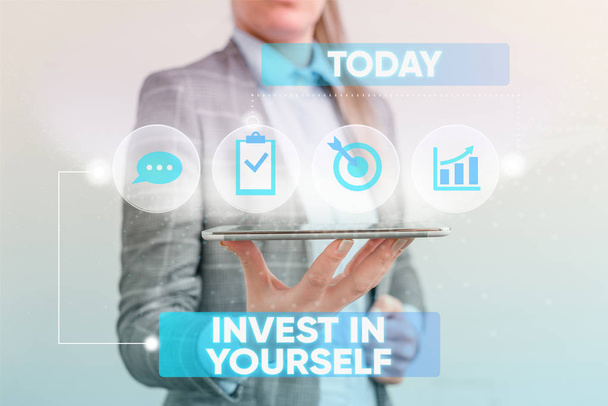 Writing note showing Invest In Yourself. Business photo showcasing learn new things or materials thus making your lot better Female human wear formal work suit presenting smart device. - Photo, Image