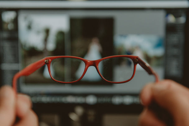 mano sosteniendo gafas rojas en el fondo del monitor
, - Foto, imagen