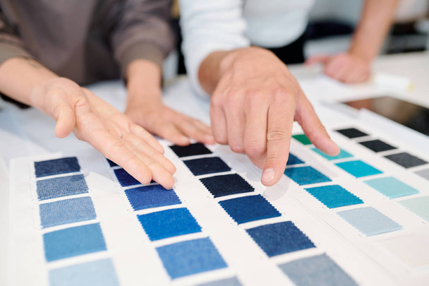 Nuori mies ja nainen muotisuunnittelijat osoittaa väri swatches tekstiilien ja valitsemalla yksi uuden järjestyksen asiakkaan
 - Valokuva, kuva