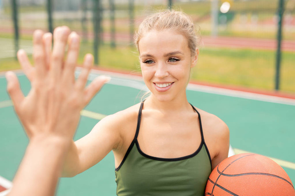 Gelukkig meisje met toothy glimlach maken High-Five gebaar met haar vriend voor of na het spel van basketbal - Foto, afbeelding