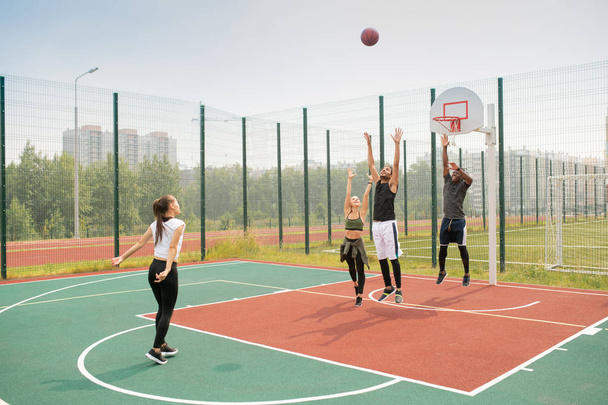 Команда молодых межкультурных друзей или студентов, работающих на баскетбольной площадке в летний день
 - Фото, изображение