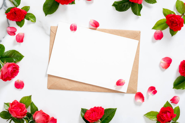 Mockup blank card with craft paper envelope, rose flowers frame and petals on marble stone background. Minimal style composition, flat lay. top view. Love letter concept. - Φωτογραφία, εικόνα