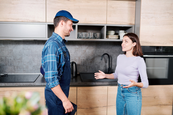 Mladá hospodyňka vysvětlující technika údržby domácnosti, jaké kuchyňské vybavení by chtěla mít - Fotografie, Obrázek