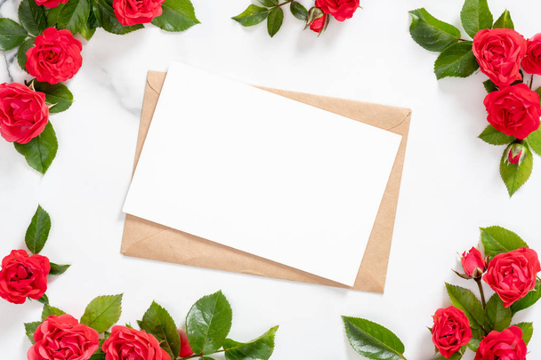 Mockup blank postcard with craft paper envelope and rose flowers frame on marble stone background. Minimal style composition, flat lay. top view. Love letter concept. - Valokuva, kuva