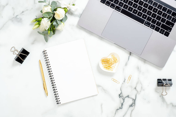 Marble office desk table with laptop computer, diary, golden stationery, flowers bouquet on white marble surface. Flat lay, top view feminine background. Fashion blogger workspace. - Zdjęcie, obraz