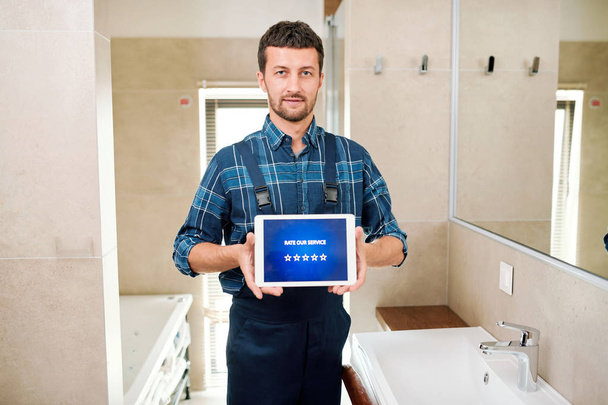Technician of contemporary repair service offering you to rate his work while holding tablet with five stars on display - Fotoğraf, Görsel
