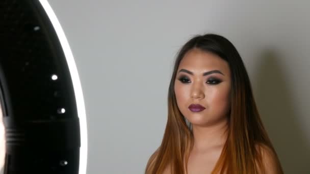 Portret van een model mooi Aziatisch meisje met lichte make-up die in de professionele studio vormt - Video
