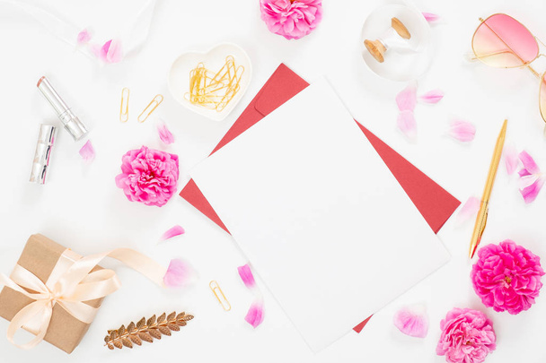 Flat lay home office desk. Top view blank paper card, pink rose flower buds, petals, female accessories, gift box on white background. Women desk, fashion blogger, beauty concept. - Φωτογραφία, εικόνα