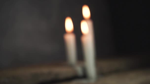 Κλείστε όμορφα καμένα κεριά σε ένα παλιό δρύινο ξύλινο τραπέζι και σκούρο γκρι φόντο τοίχου.  - Πλάνα, βίντεο
