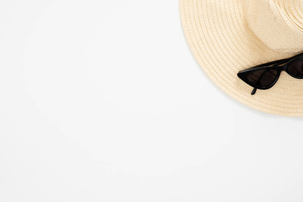 Composizione minimale in stile flat lay con cappello femminile in paglia da spiaggia e occhiali da sole su sfondo bianco. Vista dall'alto, sopraelevata. Vacanze estive. concetto di località balneare
. - Foto, immagini