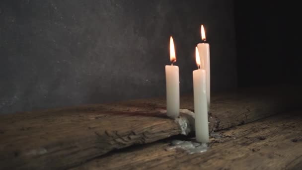 Bliska piękne spalony świece na Starym dębowym drewnianym stole i ciemnym szarym tle ściany.  - Materiał filmowy, wideo