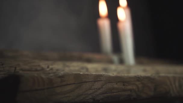 Cerrar hermosas velas quemadas en una mesa de madera de roble viejo y fondo de pared gris oscuro
.  - Metraje, vídeo