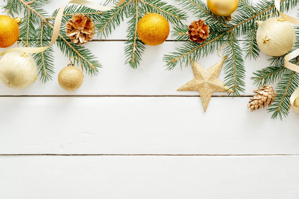 Χριστουγεννιάτικο πλαίσιο κατασκευασμένο από χρυσά διακοσμητικά, μπάλες, αστέρια, κώνους και τα κλαδιά ελάτου δέντρου σε λευκό ξύλινο φόντο. Χριστούγεννα, Πρωτοχρονιά, ιδέα για χειμερινές διακοπές. Πρότυπο πανό, υπόδειγμα καρτ ποστάλ. Επίπεδη ωοτοκίδα - Φωτογραφία, εικόνα