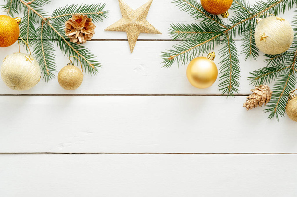 New year or Christmas golden decorations and fir tree branches on white wooden background. Flat lay, top view, copy space. Christmas, New Year, winter holiday concept. Banner mockup template - Photo, Image