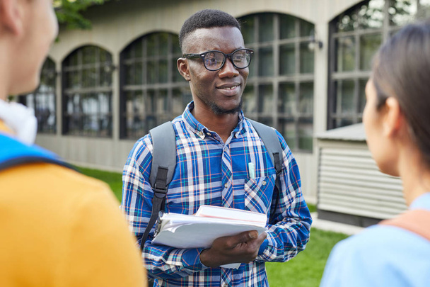 Talia się portret wesoły African-American student rozmawia z przyjaciółmi na zewnątrz w kampusie uczelni, Kopiuj przestrzeń - Zdjęcie, obraz