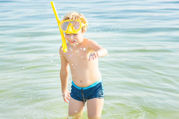 Χαριτωμένο μικρό παιδί στην παραλία. Όμορφο αγόρι κοντά στο νερό το καλοκαίρι. Καλοκαιρινές διακοπές. - Φωτογραφία, εικόνα