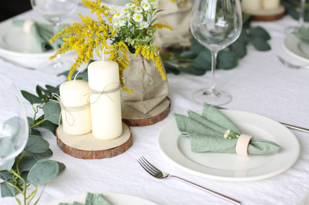 Wild flower table decor. Green linen napkins on white place and white linen tablecloth - Fotó, kép