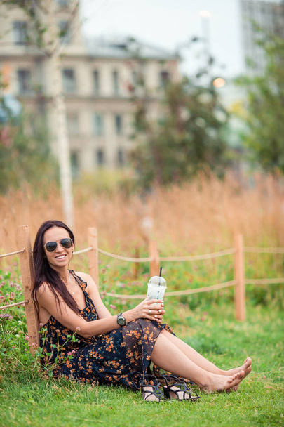 屋外でコーヒーを飲む幸せな若い都会の女性 - 写真・画像