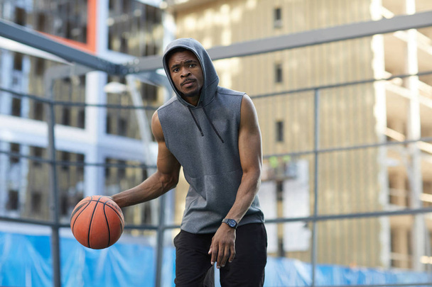 Action-Porträt eines afrikanischen Basketballspielers, der auf einem Außenplatz übt, Kopierraum - Foto, Bild