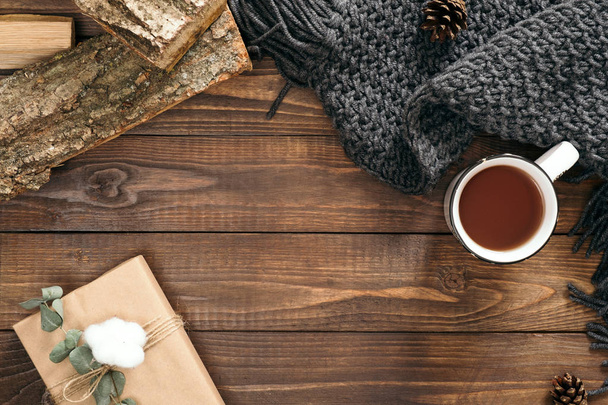Autumn composition. Cup of tea, women fashion scarf, gift box, firewood on wooden background. Flat lay, top view, copy space. Scandinavian hygge concept. - Fotografie, Obrázek