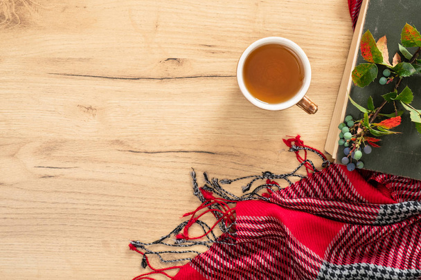 Book, knitted red scarf, cup of tea on wooden table. Flat lay, top view, copy space. Hygge autumn concept. - Фото, зображення