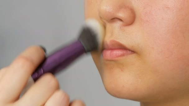 Professional makeup artist applies foundation concealer or highlighter to Asian Korean models face with special brush - Felvétel, videó
