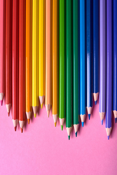 Color pencils on pink pastel background, close up. Set of colorf - 写真・画像