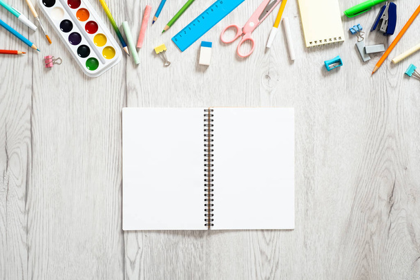 Back to school concept, creative layout with with various school supplies and blank paper notepad with copy space on wooden background. Flat lay style composition, top view, overhead. - Photo, Image