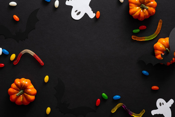 Cadre d'Halloween avec citrouilles, bonbons, fantômes isolés sur fond noir. Modèle de carte d'invitation de fête d'Halloween. Pose plate, vue du dessus, espace de copie
. - Photo, image