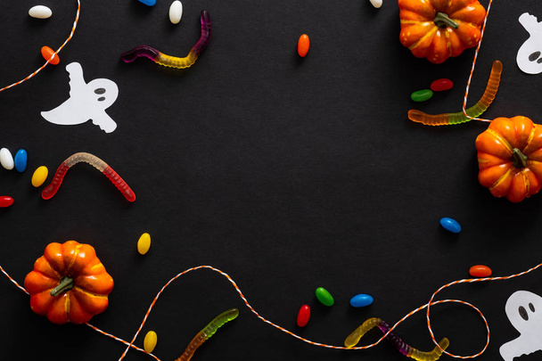 Halloween background with pumpkins, candy, rope, ghosts isolated on black. Halloween party invitation card mockup. Flat lay, top view, copy space. - Photo, image