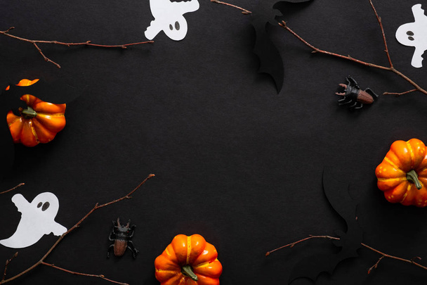 Halloween composition with ghosts, bats, pumpkins on black background. Halloween party invitation card mockup. Flat lay, top view, copy space. - Foto, afbeelding